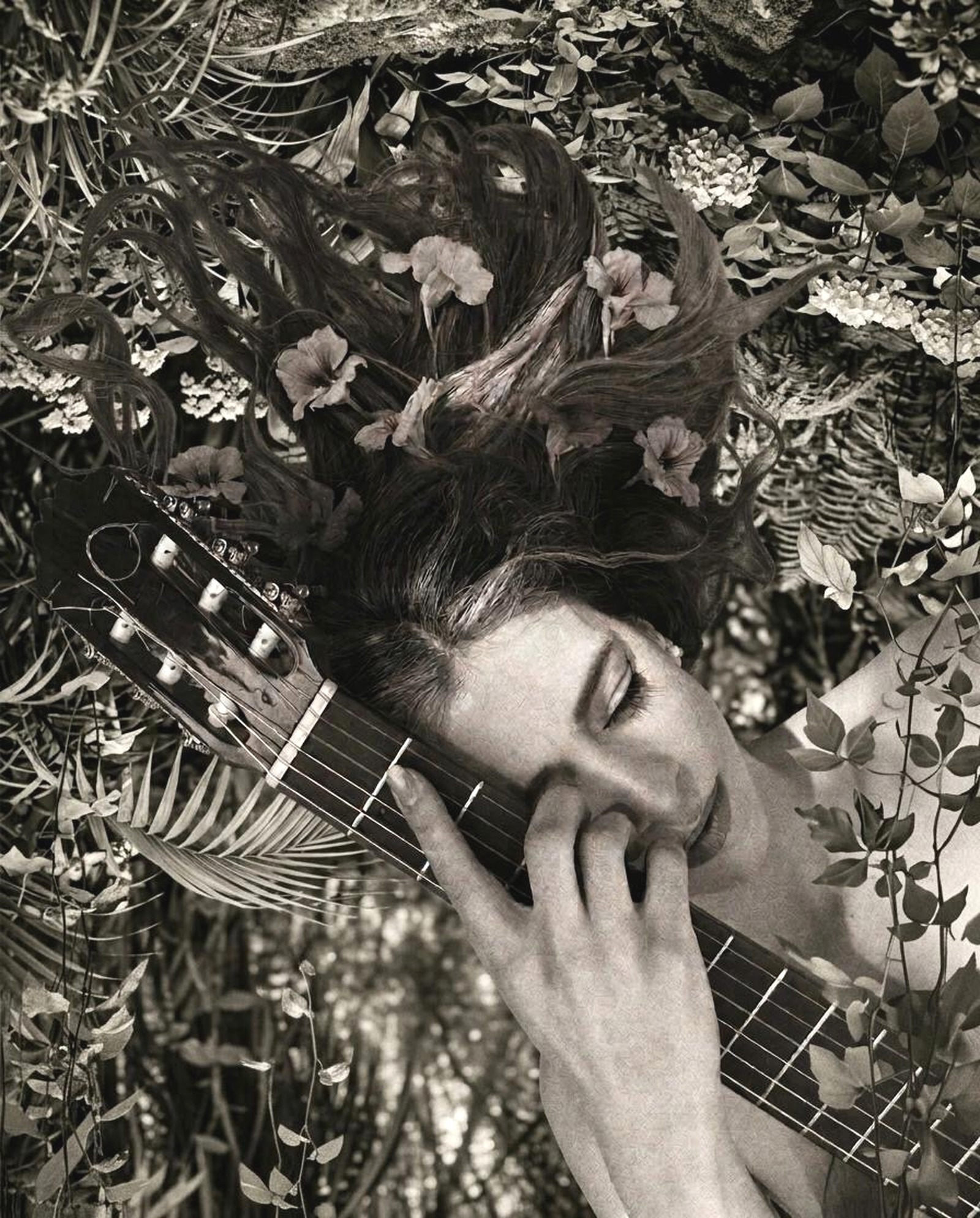 Retrato artístico en blanco y negro de Mar Sánchez con los ojos cerrados, apoyada sobre el clavijero de su guitarra española, y el cabello fundiéndose entre flores y hojas — la misma imagen de la portada de Solo Guitar